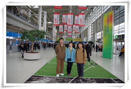 “하노버 CeBIT 박람회 전시장 내부의 넓은 로비 공간에서 일행이 중앙 통로 위에서 기념사진을 찍고 있다. 주변에는 방문객들이 이동하고, 상부에는 ‘CeBIT’가 적힌 배너들이 여러 개 걸려 있어 전시회 분위기를 보여준다.”